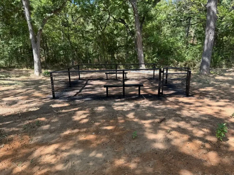 Fenced, shaded dog park with benches at Longhorn Landing RV Park