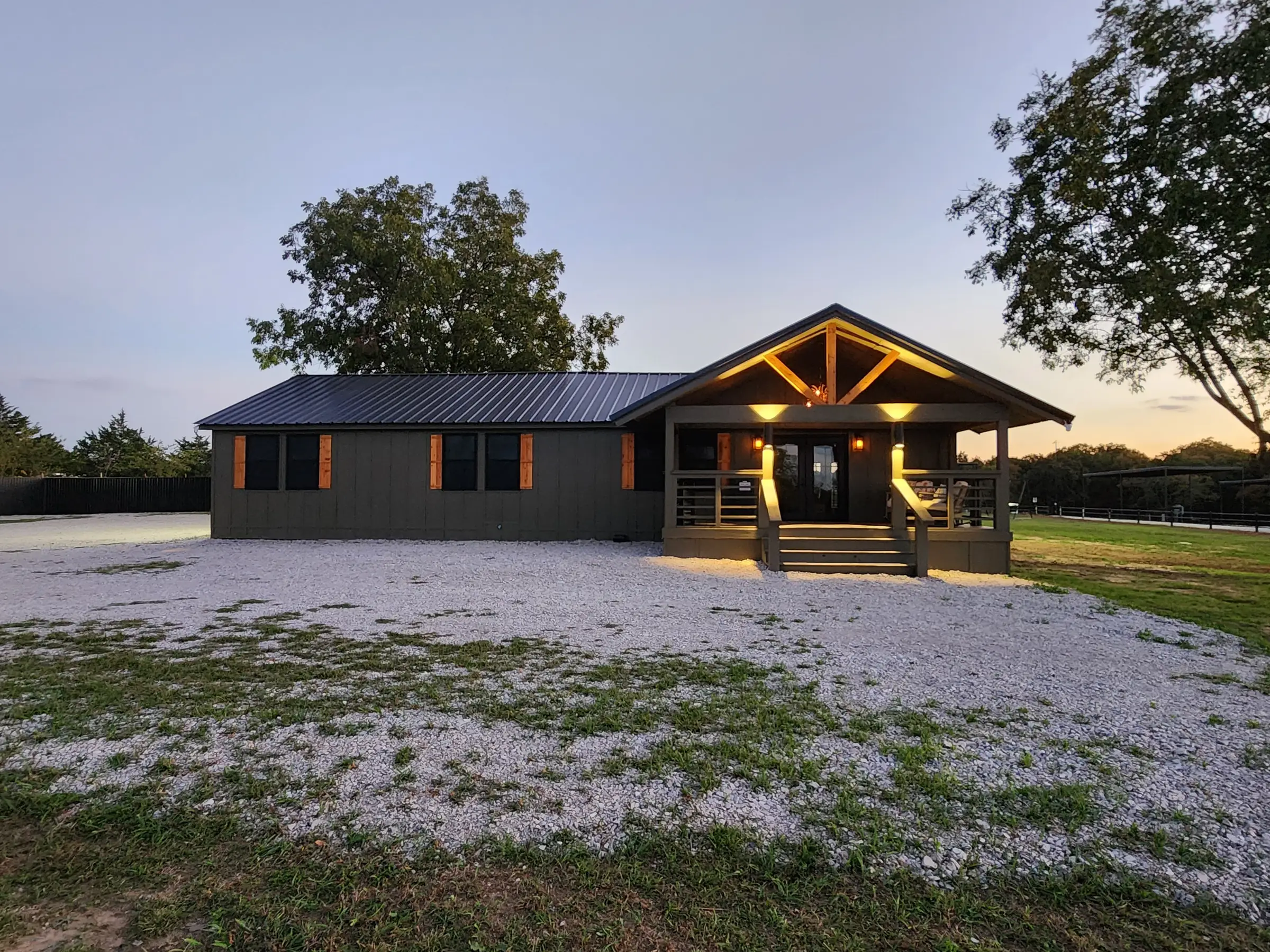 Longhorn Landing RV Park lodge with its front porch lit up at dusk in Lone Grove, OK