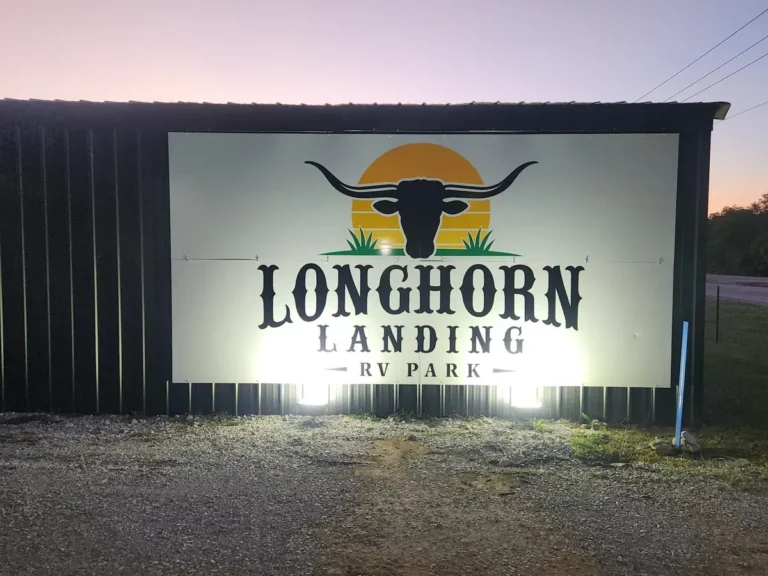 Lit Longhorn Landing RV Park sign on a black barn at night